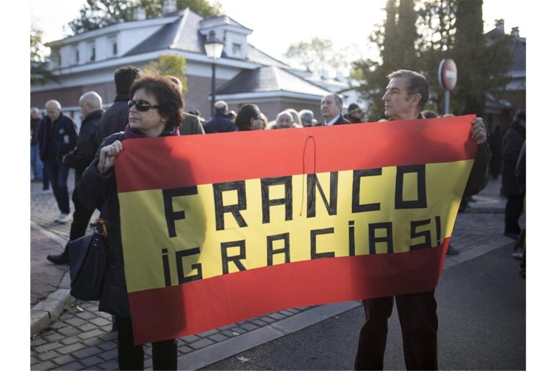 Gegner der Umbettung tragen eine spanische Flagge mit der Aufschrift „Franco Danke“. Foto: Javier Carbajal/dpa