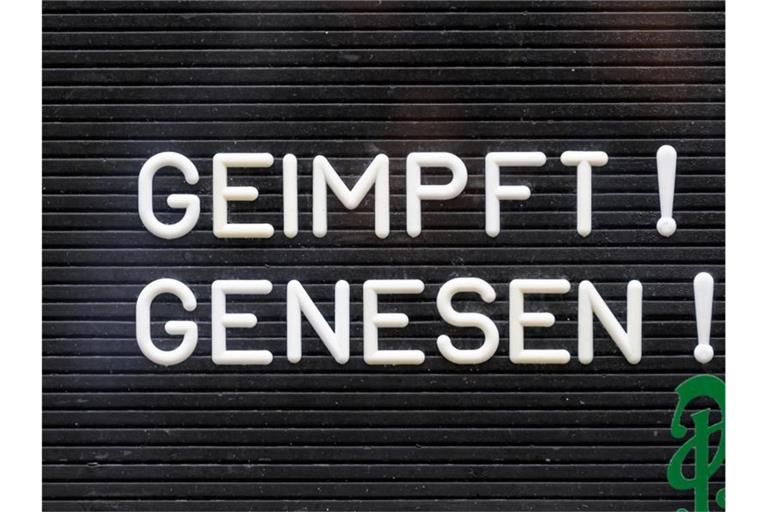 "Geimpft! Genesen!" steht auf einem Schild an einer Bar. Foto: Robert Michael/dpa-Zentralbild/dpa/Symbolbild