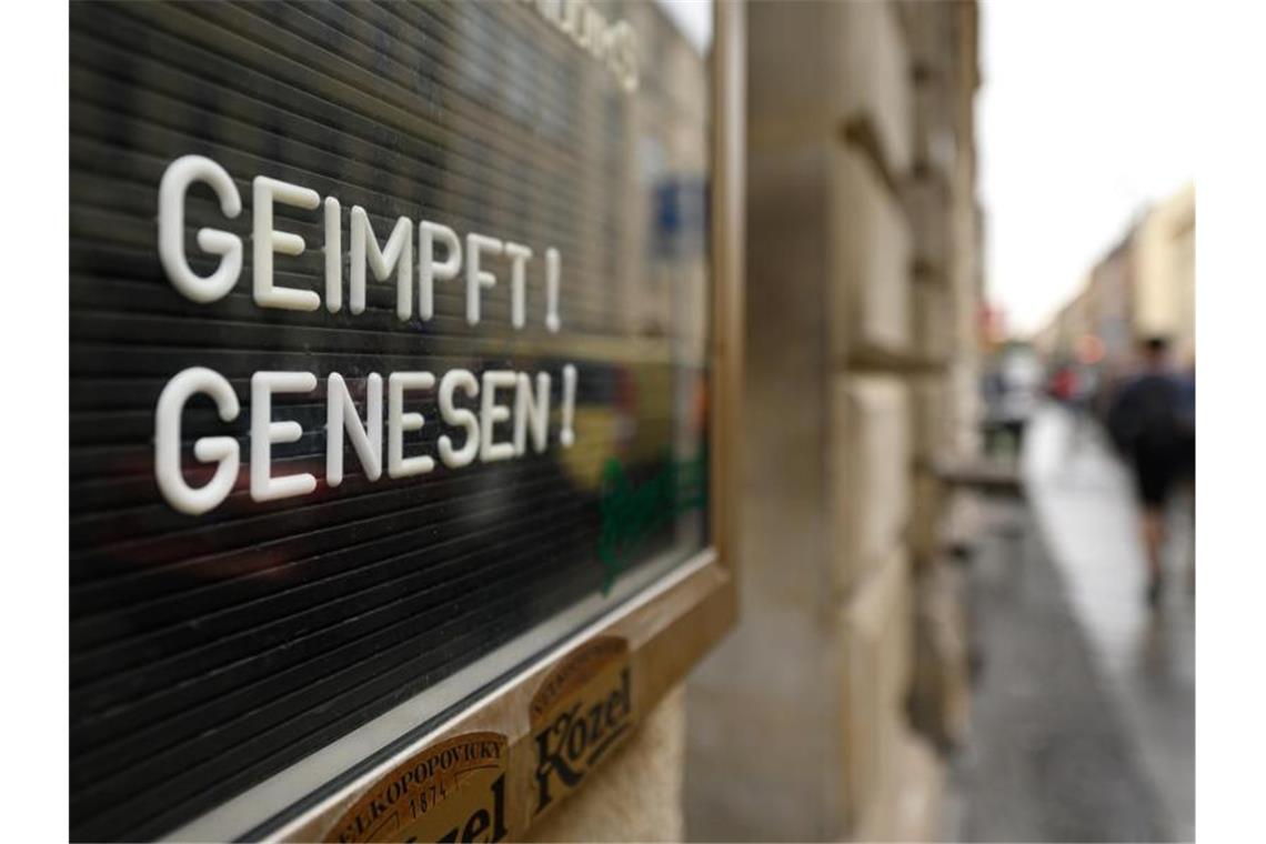 „Geimpft! Genesen!“ steht auf einem Schild an einer Bar. Foto: Robert Michael/dpa-Zentralbild/dpa/Symbolbild