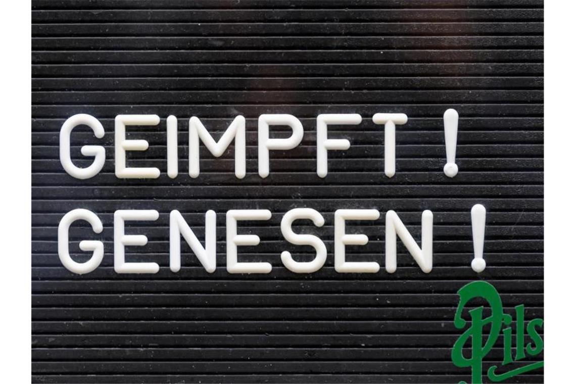„Geimpft! Genesen!“ steht auf einem Schild an einer Bar. Foto: Robert Michael/dpa-Zentralbild/dpa/Symbolbild