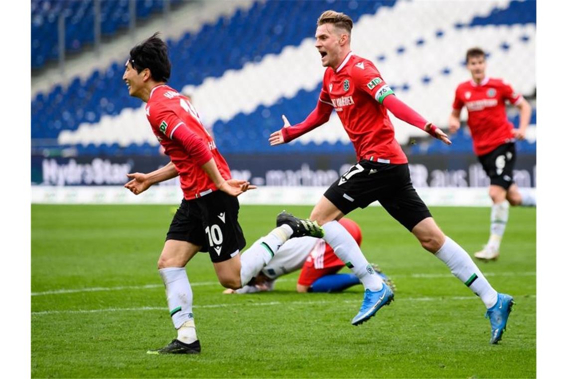 Genki Haraguchi (l) und Marvin Ducksch retteten Hannover 96 noch einen Punkt gegen den HSV. Foto: Swen Pförtner/dpa-POOL/dpa