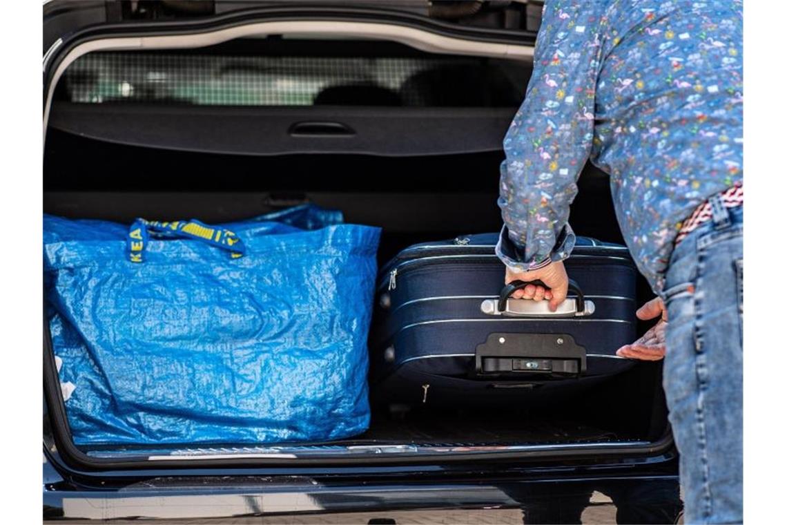 Gepackte Koffer werden in ein Fahrzeug geschoben - doch wo darf ich jetzt noch hinfahren?. Foto: Guido Kirchner/dpa