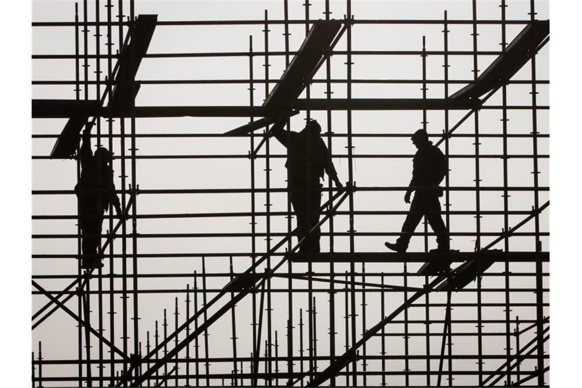 Gerüstbauer errichten in Hamburg auf einer Brückenbaustelle in der Hafencity ein Gerüst. Foto: Christian Charisius/dpa/Symbolbild