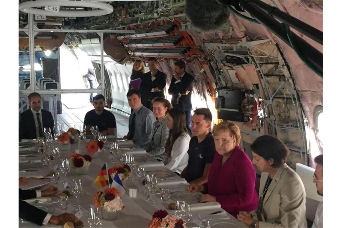 Gespräche im Rumpf eines halbfertigen Jets: Bundeskanzlerin Angela Merkel (4.v.r.) und der französische Staatspräsident Emmanuel Macron (l.) in einer Montagehalle von Airbus. Foto: Christian Böhmer/dpa