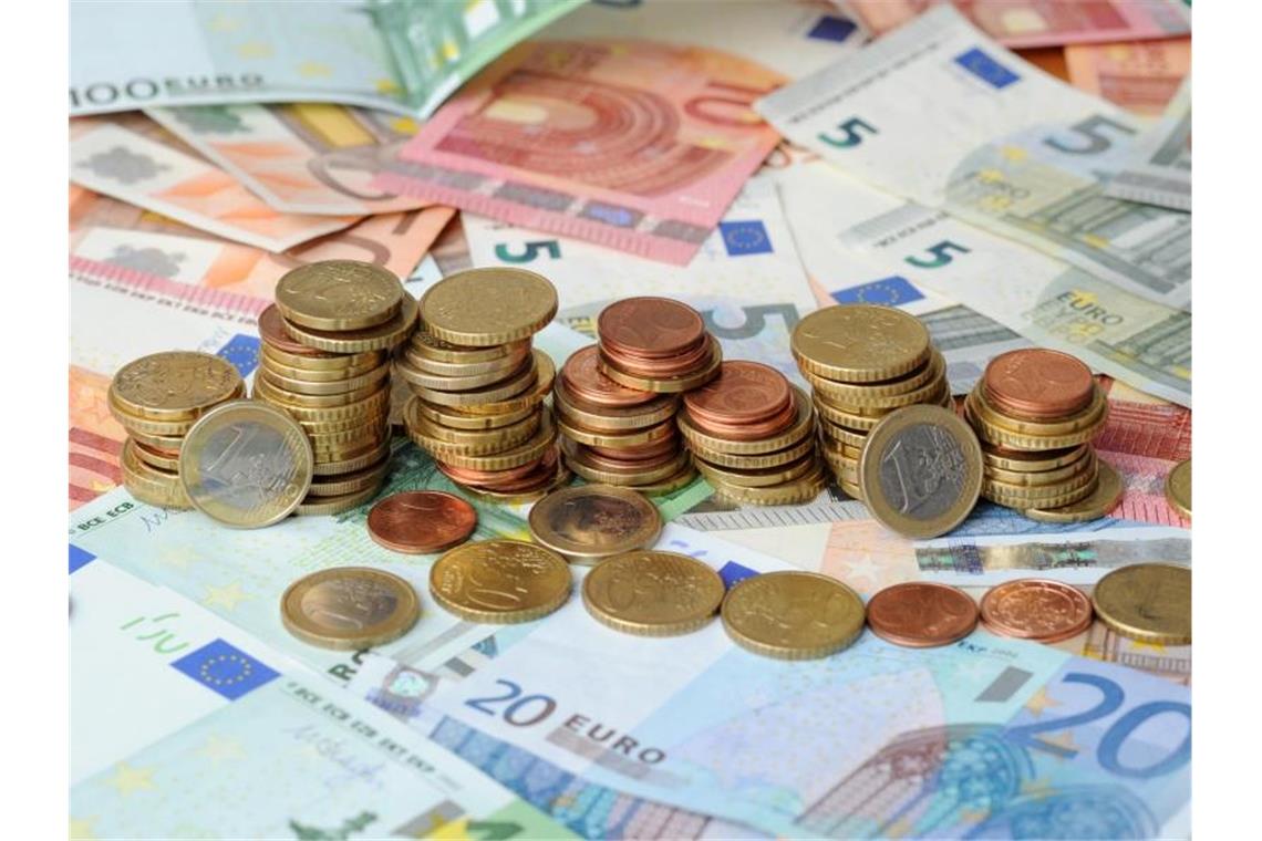 Gestapelte Geldmünzen liegen auf Geldscheinen. Foto: Tobias Hase/dpa/Archivbild