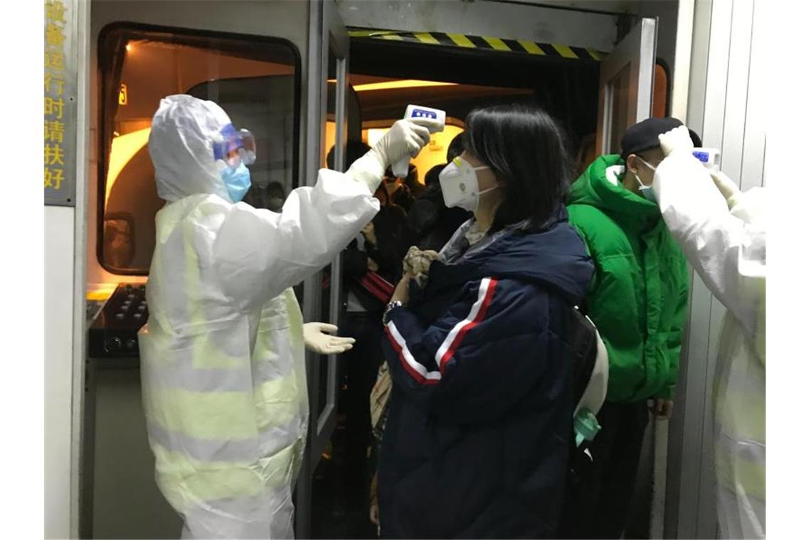 Gesundheitsbeamte kontrollieren am Flughafen von Peking die Körpertemperatur von Reisenden aus der Stadt Wuhan. Foto: Emily Wang/AP/dpa
