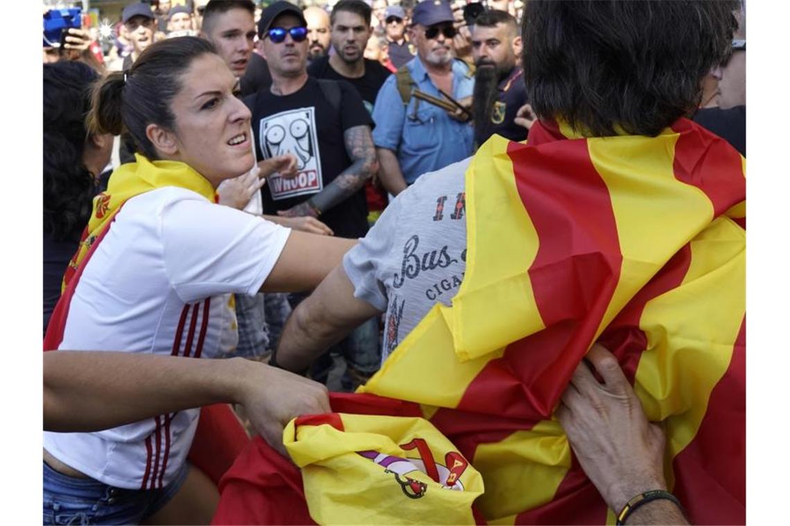 Geteiltes Spanien vor dem ersten Jahrestag des Unabhängigkeitsreferendums: Eine Frau, die eine spanische Flagge trägt, schlägt einen Mann, der sich in eine katalonische Flagge gehüllt hat. Foto: Daniel Cole/AP/dpa