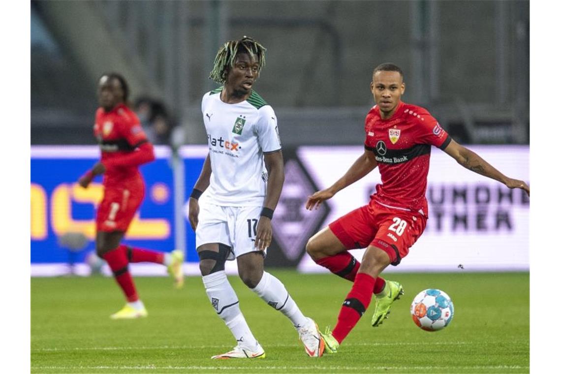 Gladbachs Kouadio Kone (l) und Stuttgarts Nikolas Nartey kämpfen um den Ball. Foto: David Inderlied/dpa