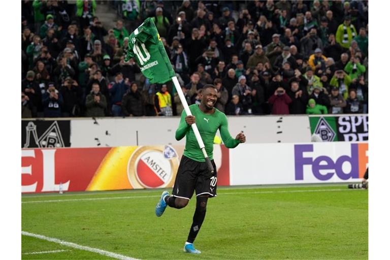 Gladbachs Marcus Thuram feiert mit einer Eckfahne den 2:1-Heimsieg über AS Rom. Foto: Federico Gambarini/dpa