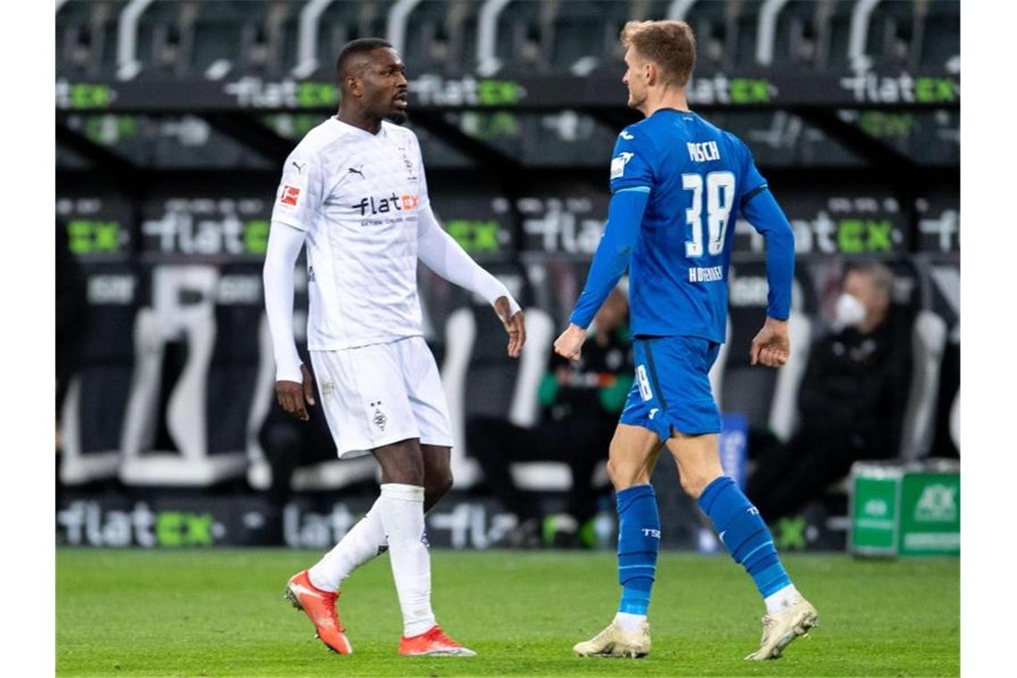 Gladbachs Marcus Thuram (l) hatte Hoffenheims Stefan Posch ins Gesicht gespuckt. Foto: Marius Becker/dpa-Pool/dpa