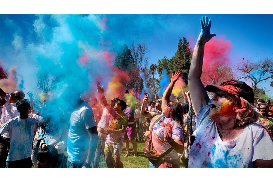 Gläubige jubeln und tanzen, als farbiges Pulver auf sie geworfen wird, um Holi zu feiern.