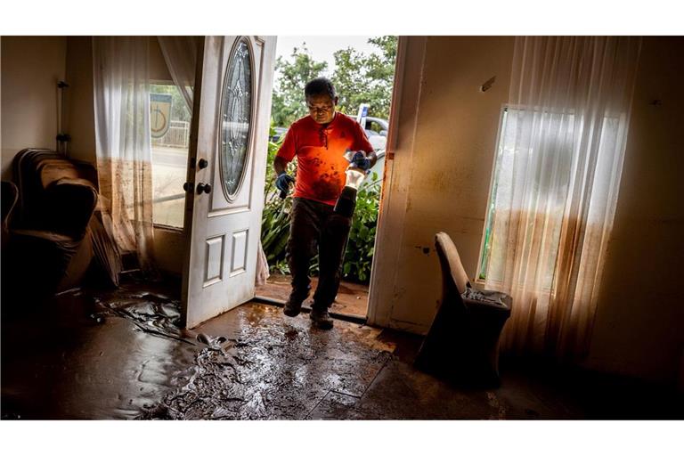 Glenn Duquez, stellvertretender Pastor der Church of God Jesus is Alive Fellowship, trägt eine Lampe in das schlammdurchtränkte Kirchengebäude, um nach der Flut aufzuräumen.