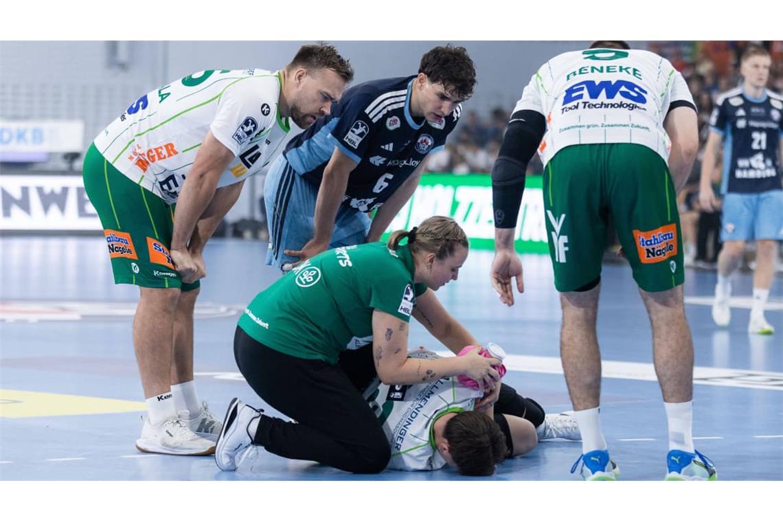 Göppingens Spielmacher Ole Pregler liegt in der Sporthalle Hamburg am Boden und wird an seiner Schulter von Frisch-Auf-Physiotherapeutin Katharina Leßig behandelt.