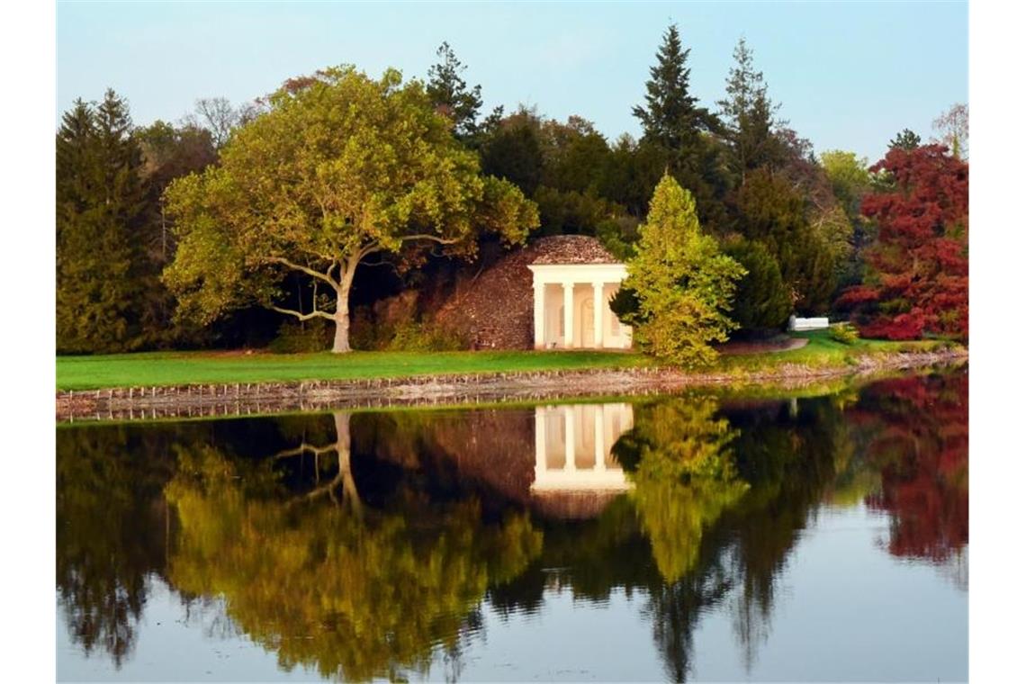 Goldener Oktober: Herbstlich gefärbte Bäume und das Nymphaeum spiegeln sich im See im Wörlitzer Park. Foto: Waltraud Grubitzsch/dpa-Zentralbild/dpa