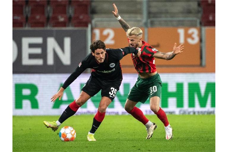Goncalo Paciencia von Eintracht Frankfurt (l) schirmt den Ball gegen Augsburgs Niklas Dorsch ab. Foto: Matthias Balk/dpa