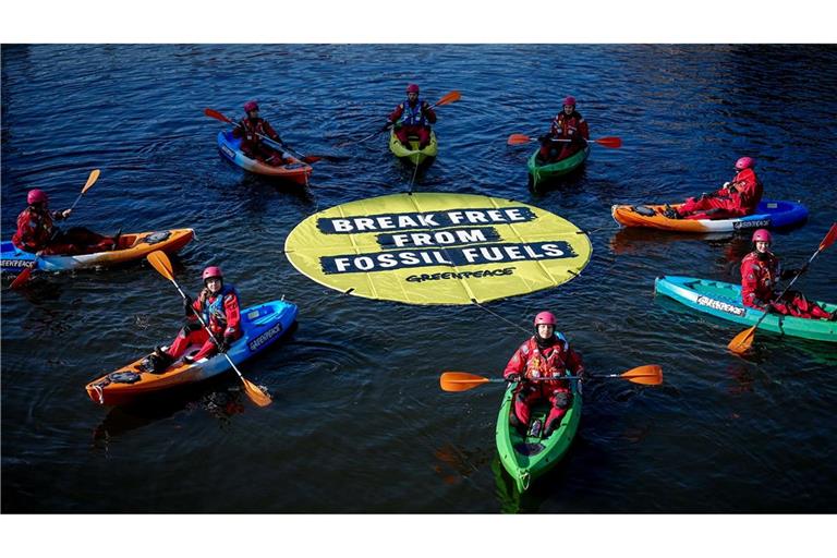 Greenpeace fordert bei einer Aktion am Veranstaltungsort die Abkehr von fossilen Energien.