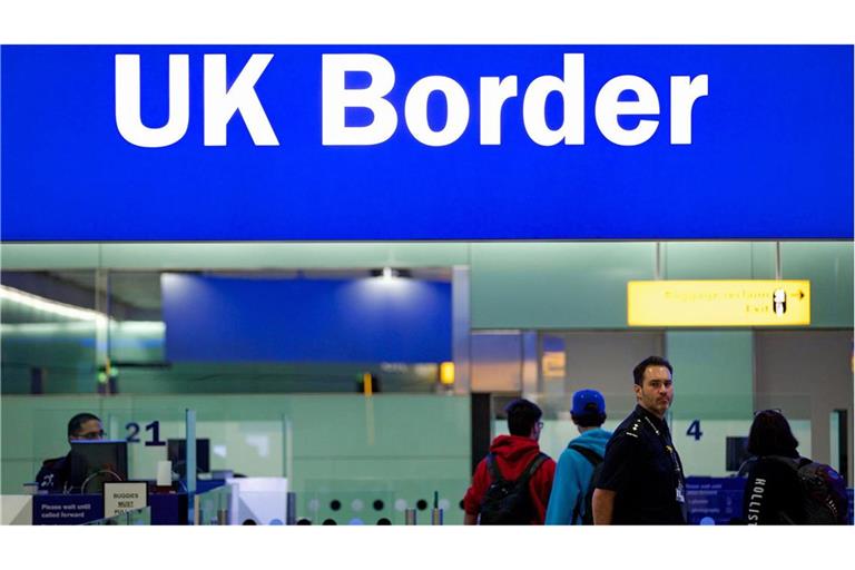 Grenzbeamte stehen am Flughafen Heathrow unter einem Schild mit der Aufschrift „UK Border“. Aktuell gibt es Probleme bei der Passkontrolle.
