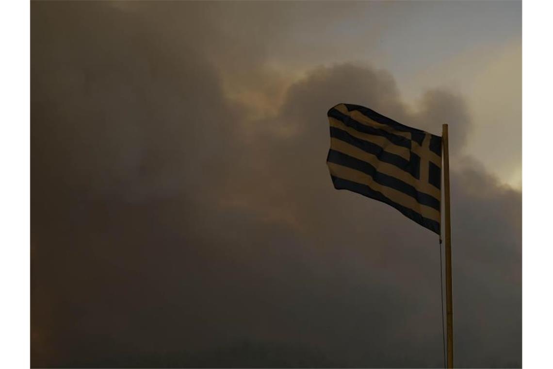 Griechische Flagge im Rauch eines Brandes: Brach das Feuer in der Garage im Rumpf der Fähre aus?. Foto: Petros Karadjias/AP/dpa/Symbolbild