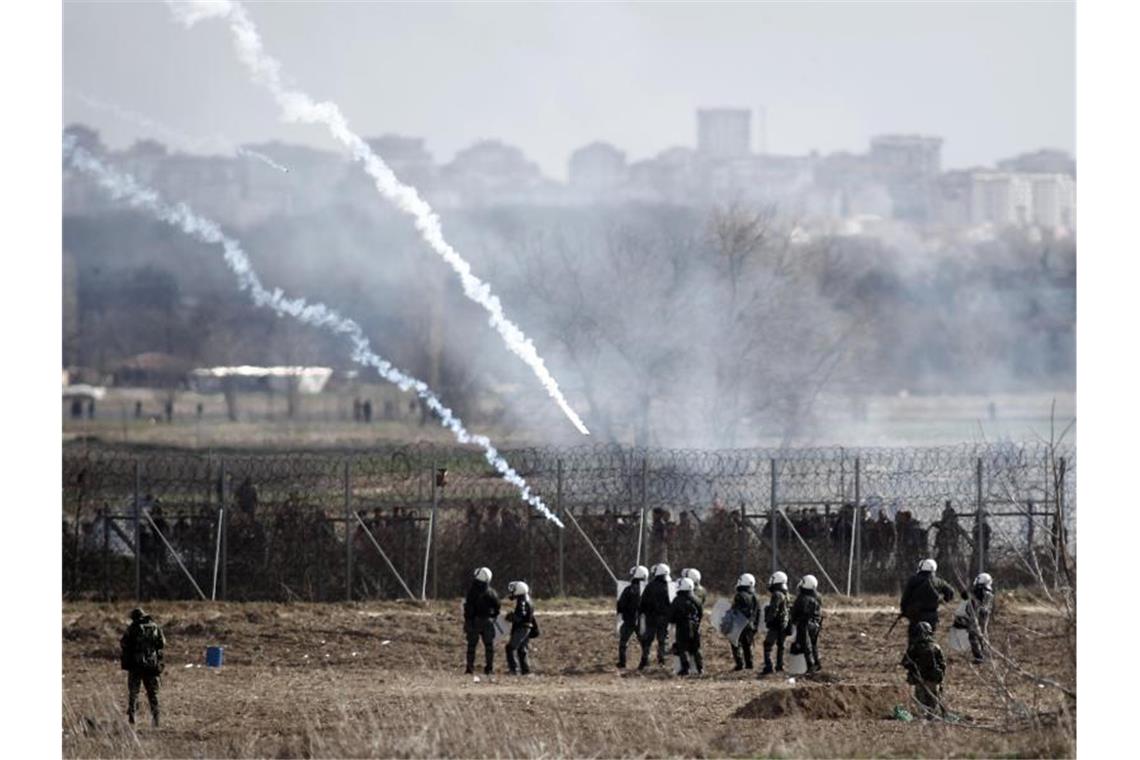 Griechische Polizisten feuern Tränengas ab. Foto: Giannis Papanikos/AP/dpa