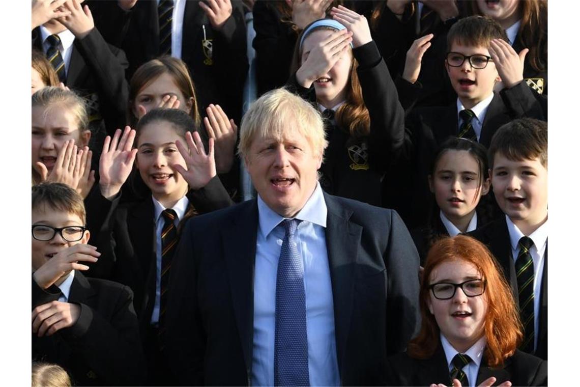 Großbritanniens Premierminister Boris Johnson (M) steht zwischen Schüler bei seinem Besuch eines Colleges. Foto: Stefan Rousseau/PA Wire/dpa