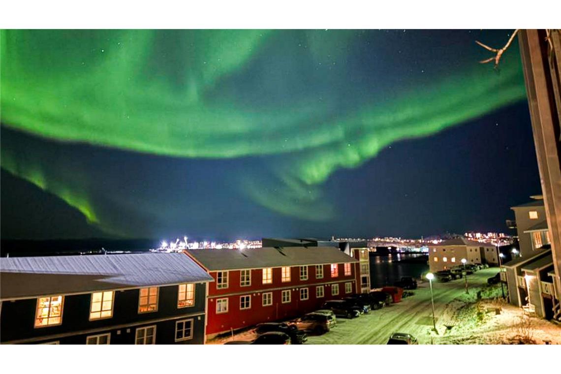 Grün leuchtende Nordlichter bedecken den Himmel über der Stadt Nuuk.