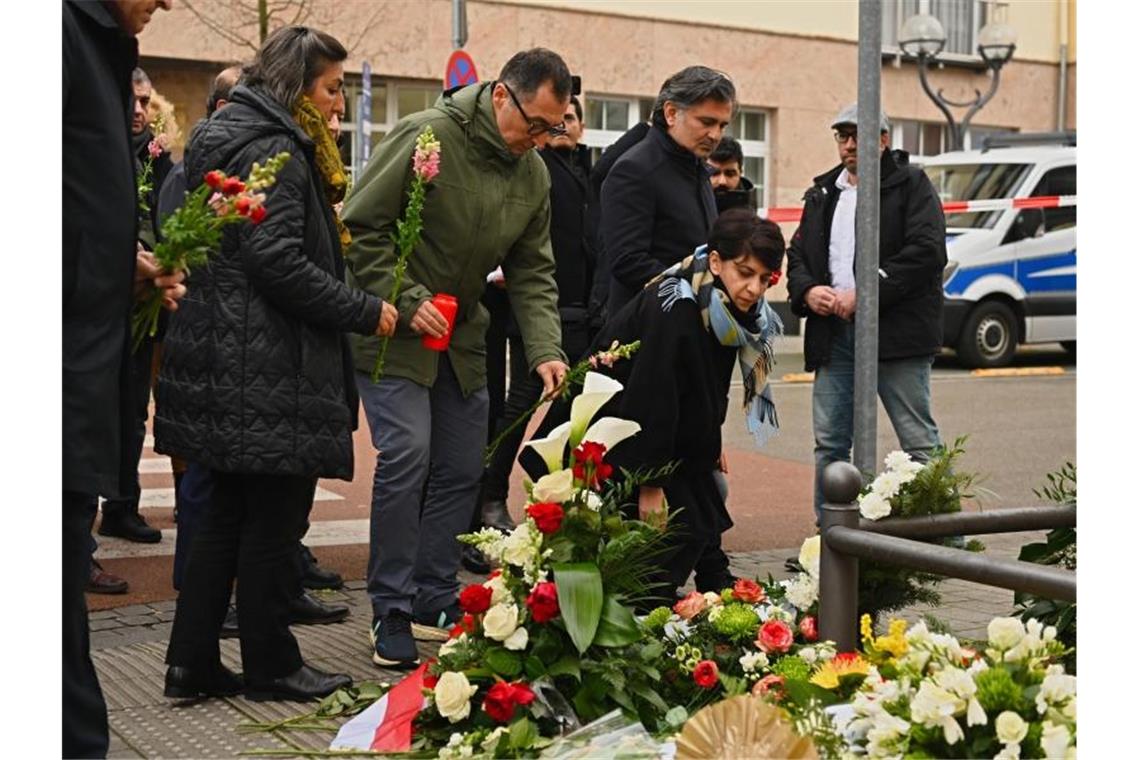 Grünen-Politiker Cem Özdemir (M) legt in der Nähe des Tatortes in Hanau Blumen nieder. Foto: Nicolas Armer/dpa