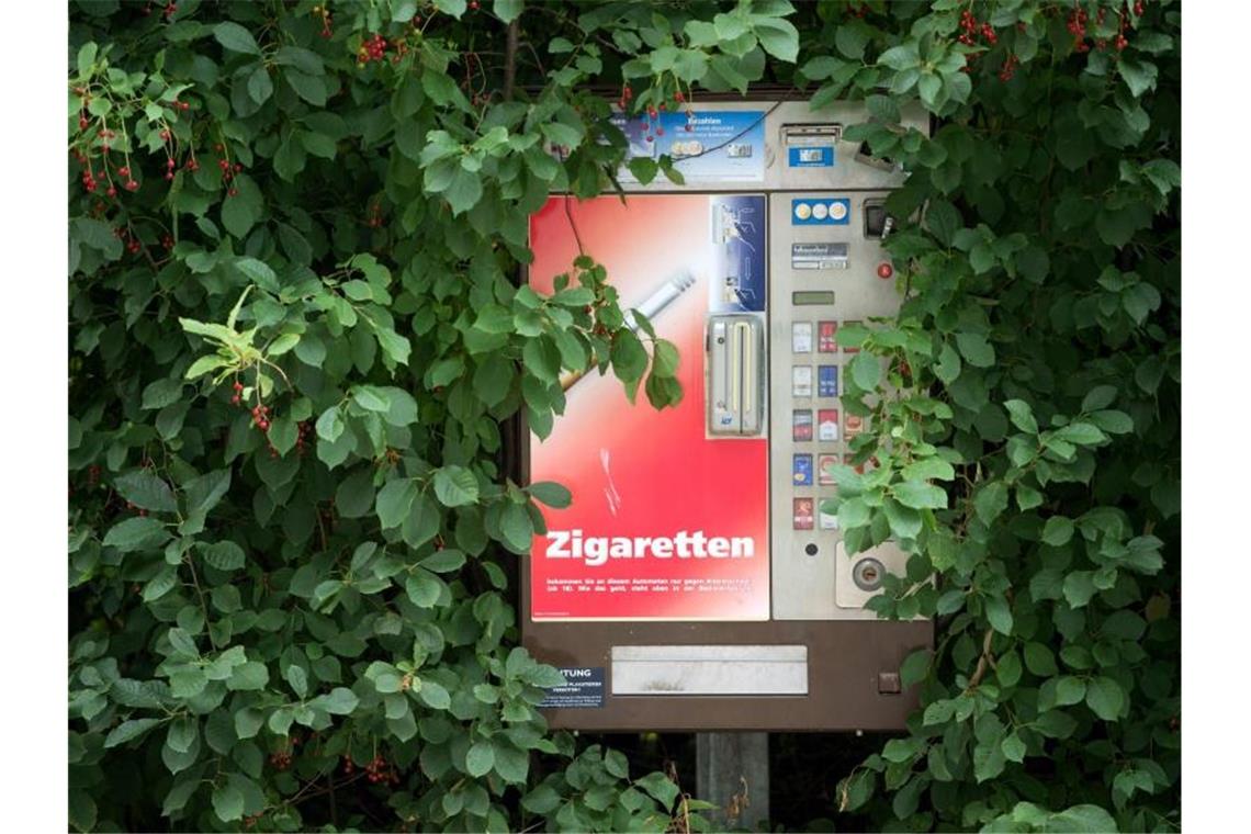 Grünes Blattwerk umrahmt einen Zigarettenautomaten. Foto: Arno Burgi/dpa-Zentralbild/dpa