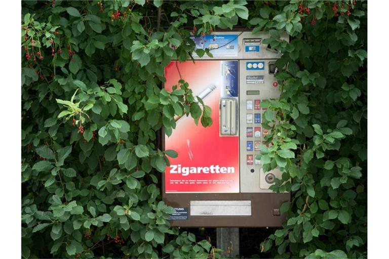 Grünes Blattwerk umrahmt einen Zigarettenautomaten. Foto: Arno Burgi/dpa-Zentralbild/dpa