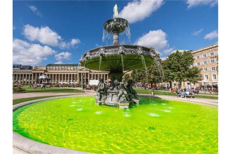 Grünes Wasser sprudelt aus einem Brunnen am Schlossplatz. Foto: Christoph Schmidt/dpa