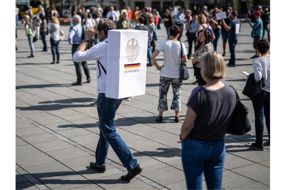 "Grundgesetz" steht auf einem Schild an dem Rücken eines Teilnehmers einer Demonstration. Foto: Christoph Schmidt/dpa
