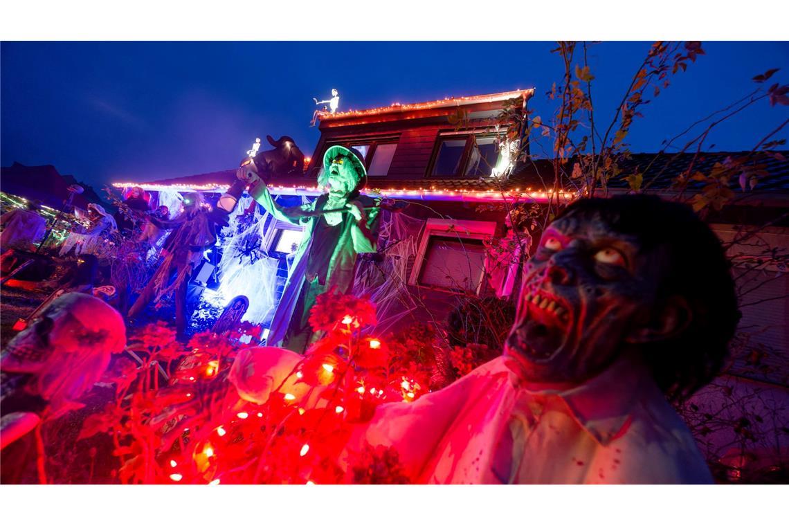 Gruselige Figuren stehen in Mettmann vor einem beleuchteten Halloween-Haus.