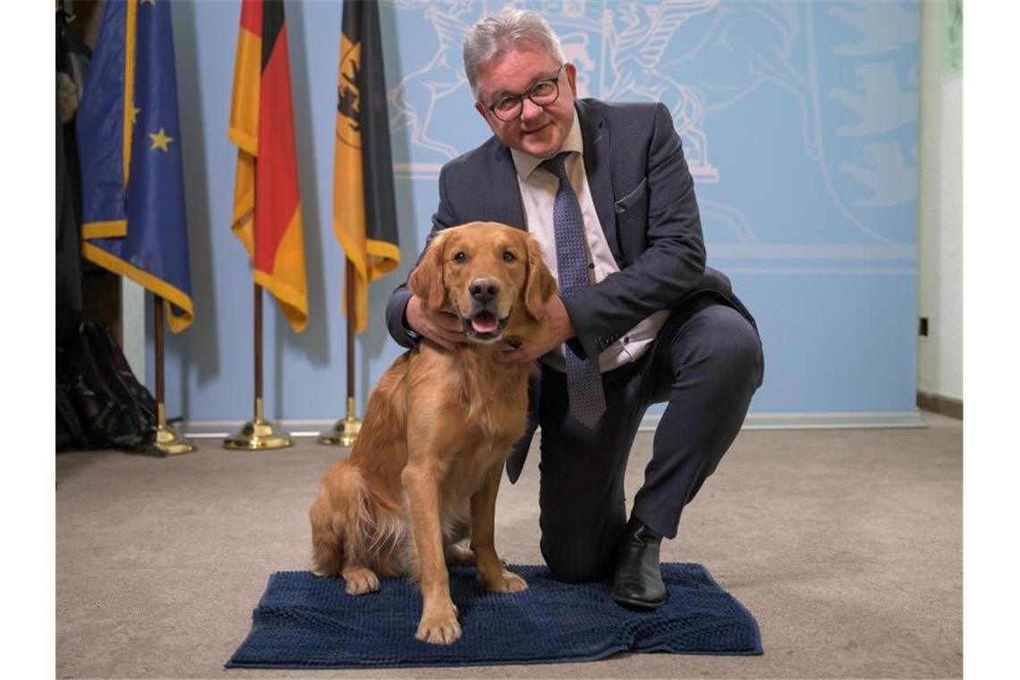 Guido Wolf (CDU), Justizminister von Baden-Württemberg, sitzt neben dem Therapiebegleithund Watson. Foto: Sebastian Gollnow/dpa