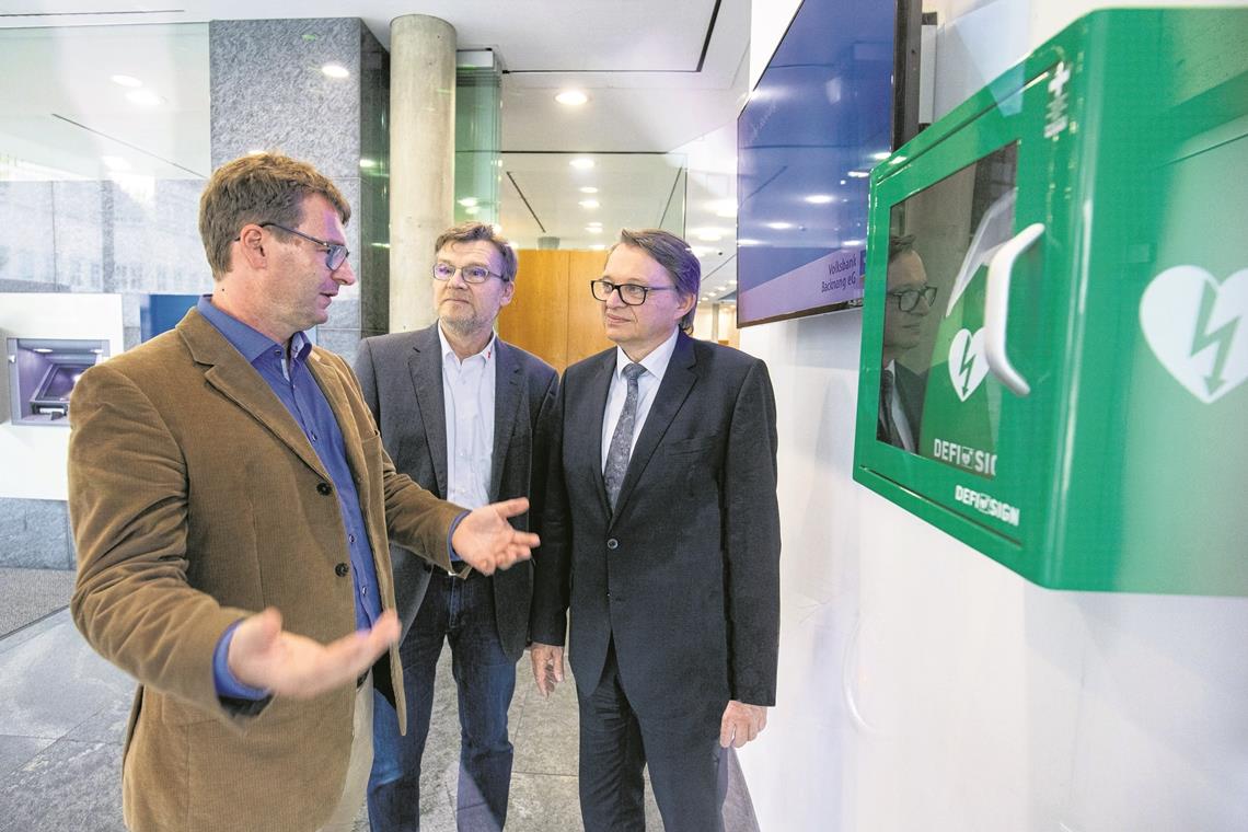 Gut sichtbar und öffentlich zugänglich hängt der Defibrillator im Foyer der Volksbank Backnang. Doch das ist nicht überall der Fall: Thomas Eul (links) und Klaus-Dieter Fackler (Mitte), hier mit Volksbank-Chef Jürgen Beerkircher, wollen Überzeugungsarbeit leisten. Foto: A. Becher