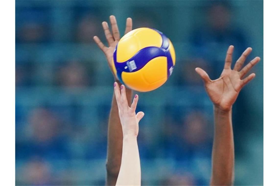 Händen greifen in einem Spiel nach einem Volleyball. Foto: Uwe Anspach/dpa/Symbolbild