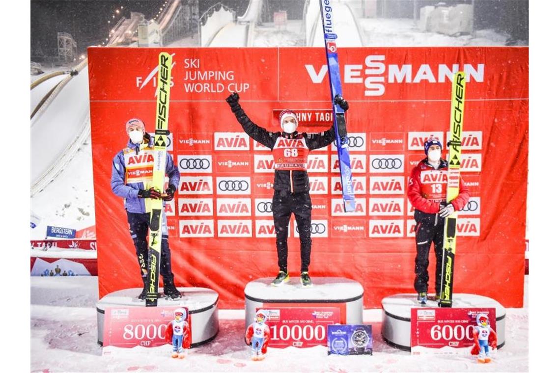 Halvor Egner Granerud (M) jubelt auf dem Podium nach seinem Sieg mit dem Zweiten, Karl Geiger (l) und dem Drittplatzierten Stefan Kraft. Foto: Tumaschow/NordicFocus/dpa