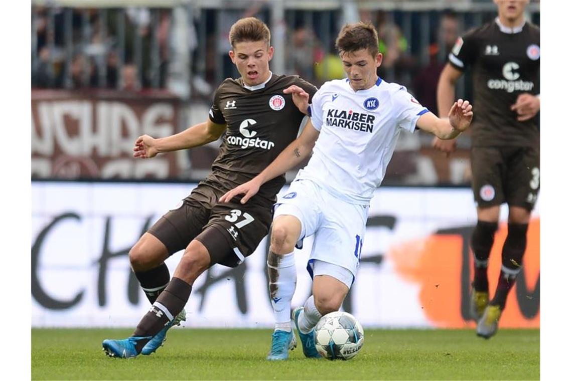 Hamburgs Finn Ole Becker (l.) und Marvin Wanitzek von Karlsruhe kämpfen um den Ball. Foto: Daniel Bockwoldt/dpa