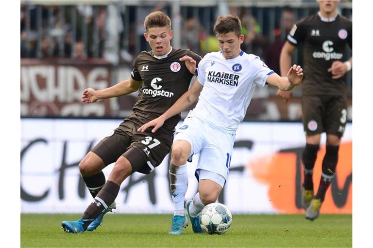 Hamburgs Finn Ole Becker (l) und Marvin Wanitzek von Karlsruhe kämpfen um den Ball. Foto: Daniel Bockwoldt/dpa/Archivbild