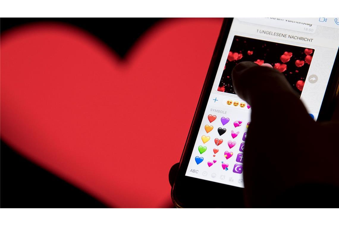 Hand aufs Handy - das rote Herz zählt zu den beliebtesten Emojis. (Archivbild)