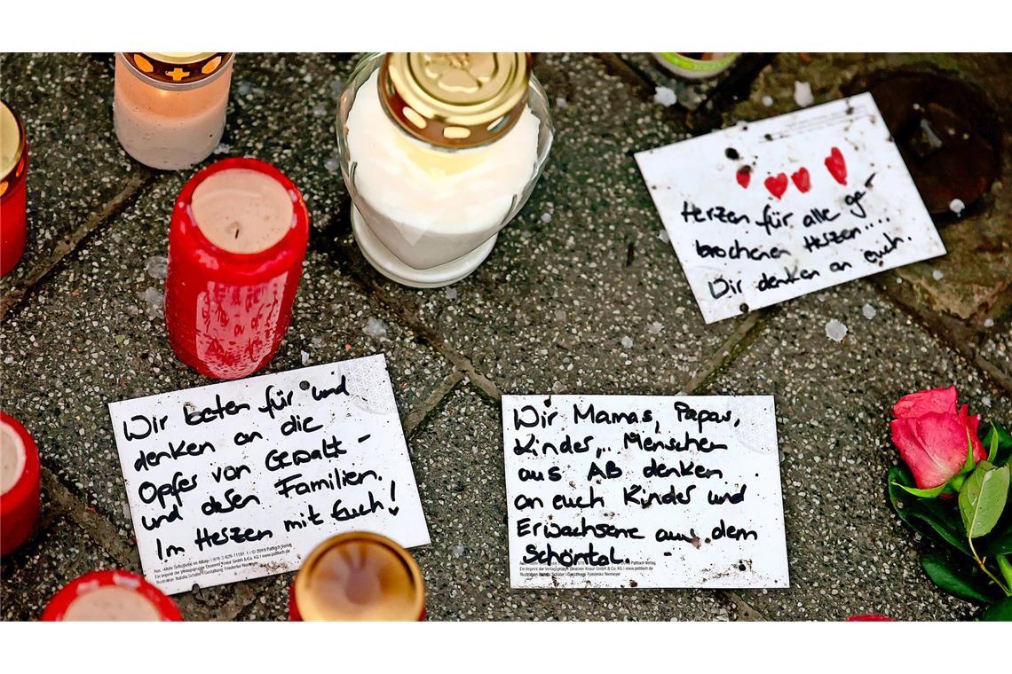 Warum war Enamullah O. noch in Deutschland? Handgeschriebene Trauerbekundungen liegen neben Trauerkerzen nach dem tödlichen Angriff in Aschaffenburg nahe dem Tatort auf dem Boden.