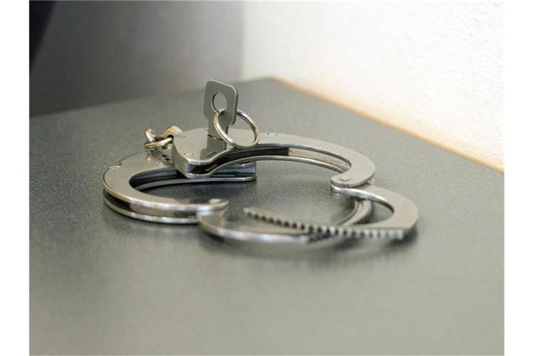 Handschellen liegen auf einem Tisch. Foto: Armin Weigel/dpa/Symbolbild