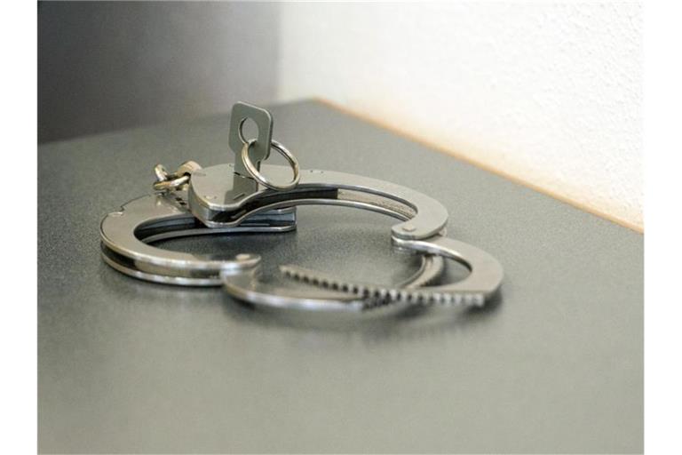 Handschellen liegen auf einem Tisch. Foto: Armin Weigel/dpa