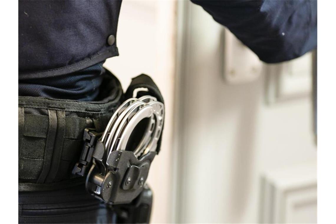 Handschellen sind an einem Gürtel eines Beamten befestigt. Foto: Frank Molter/dpa/Archivbild