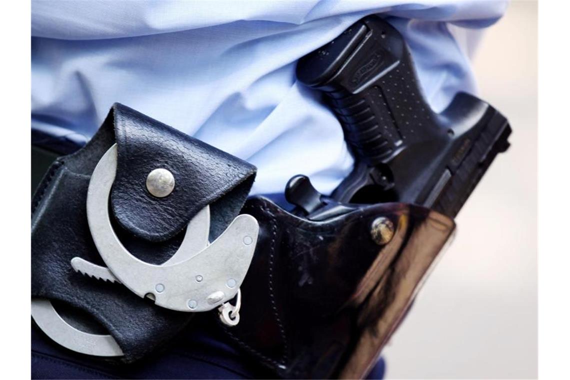 Handschellen und Pistole am Gürtel eines Polizisten. Foto: Oliver Berg/dpa/Archivbild