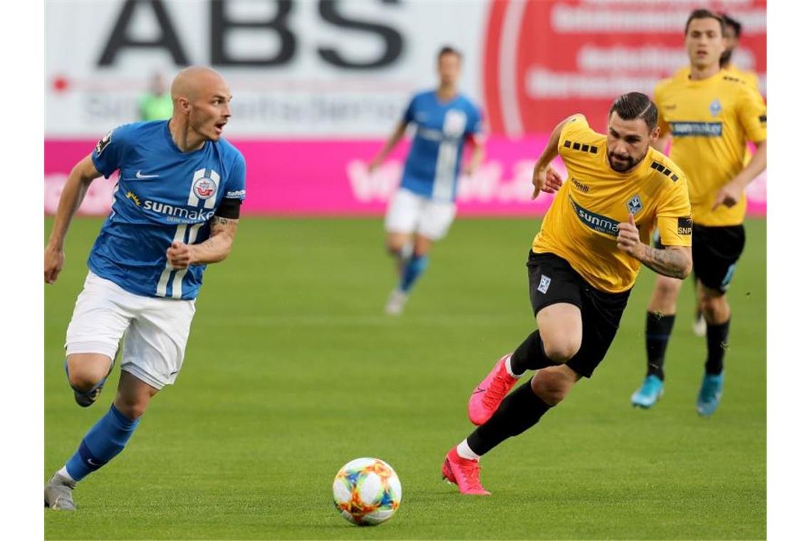 SV Waldhof mit Sieg in Rostock Hansa-Spieler Korbinian Vollmann (l-r) und der Mannheimer Marcel Hofrath im Zweikampf. Foto: Bernd Wüstneck/dpa-Zentralbild/dpa