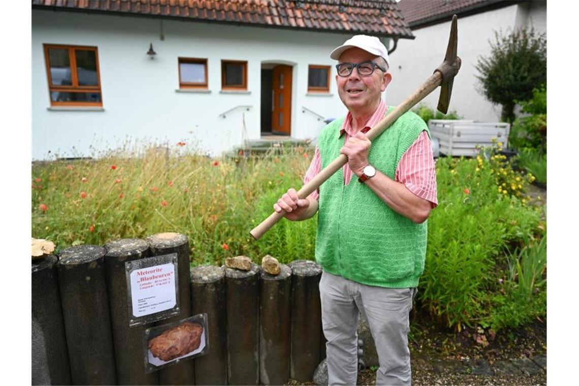 Hansjörg Bayer aus Blaubeuren steht in seinem Garten, wo er den Steinmeteoriten mit dem Pickel herausgehebelt hat. Foto: Felix Kästle/dpa