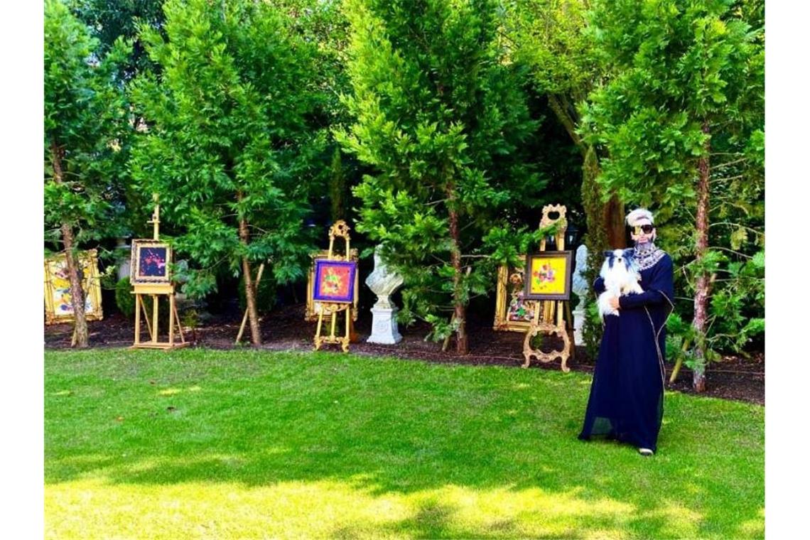 Harald Glööckler steht vor Werken seiner Kunstausstellung in seinem Garten. Foto: Glööckler/Privat/dpa