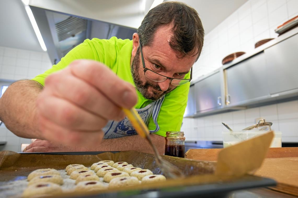 Harald Kluge tröpfelt für die Husarenbrötchen flüssiges Johannisbeergelee in die Mulde, die er vor dem Backen in den Teig gedrückt hat. Foto: A. Becher