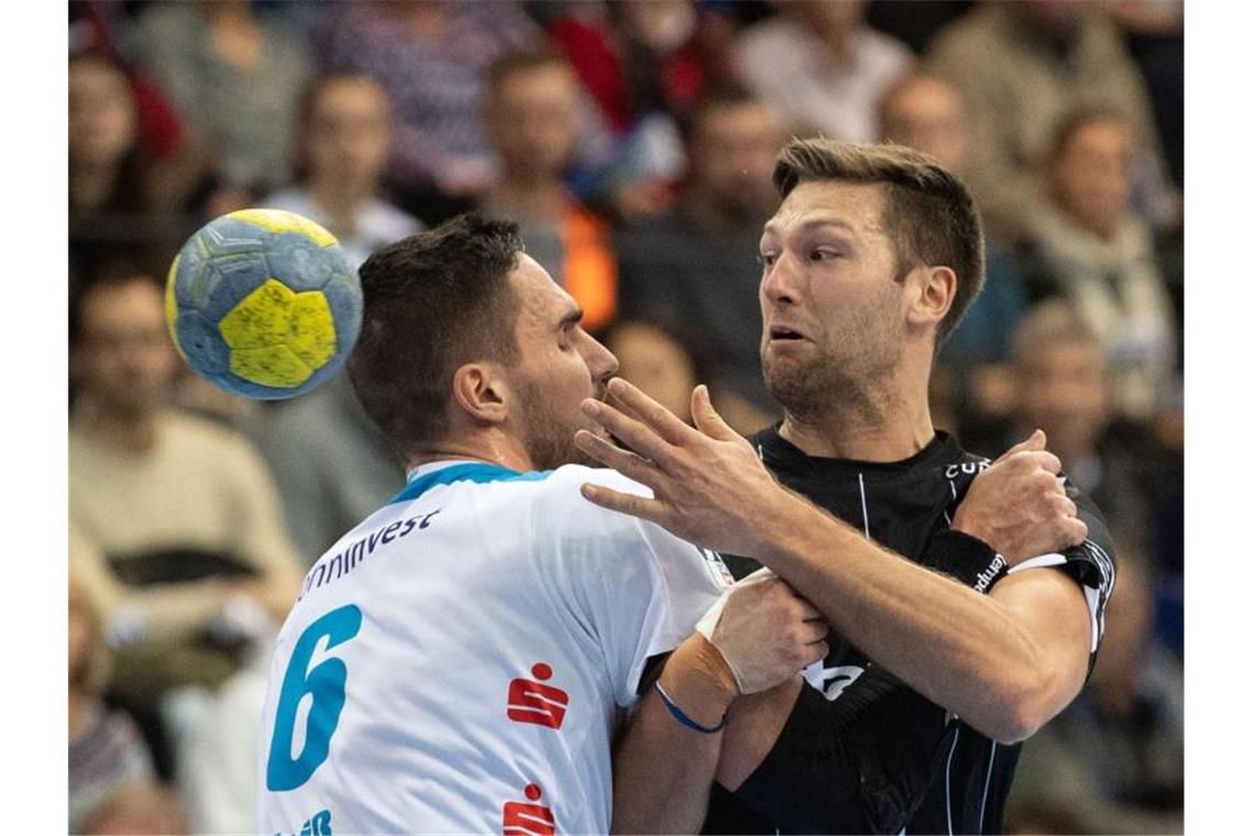 Harald Reinkind (r) vom THW Kiel wird von TVB-Spieler Dominik Weiß gebremst. Foto: Marijan Murat/dpa