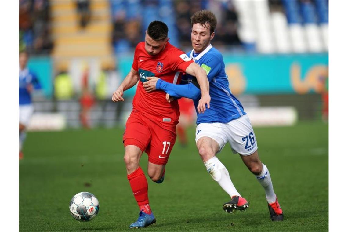 1. FC Heidenheim lässt große Chance aus: 0:2 in Darmstadt Heidenheims Maurice Multhaup (l.) und Darmstadts Matthias Bader kämpfen um den Ball. Foto: Thomas Frey/dpa