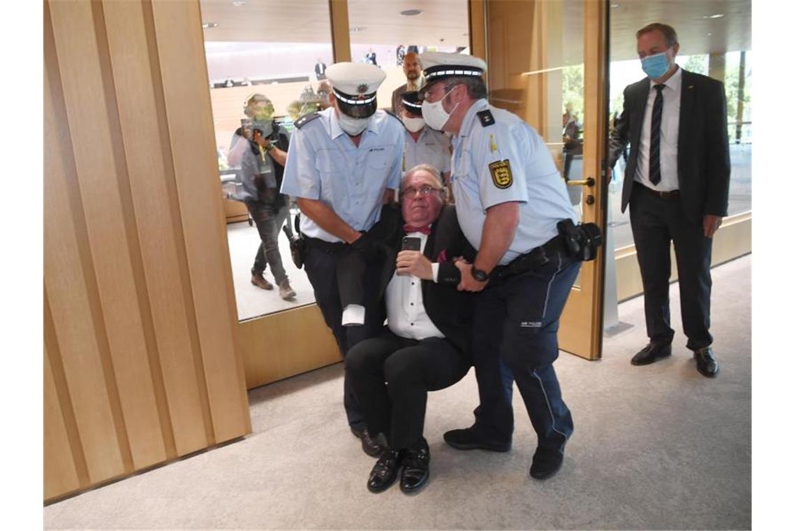 Heinrich Fiechtner (parteilos, M) wird von Polizeibeamten aus dem Landtag von Baden-Württemberg getragen. Foto: Marijan Murat/dpa